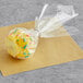 A yellow cake pop with sprinkles wrapped in plastic.
