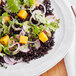 A white plate with black rice and vegetables.