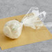 A white frosted carrot cake pop in a plastic bag.