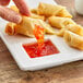 A hand dipping a spring roll into Pantai Spring Roll Sauce.