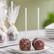 A white plate of individually wrapped chocolate cake pops.
