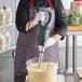 A person using an AvaMix medium-duty immersion blender on a counter in a professional kitchen.
