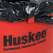A red Continental Huskee 44 gallon round trash can with a black plastic bag inside.