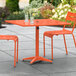 An orange table with two chairs on an outdoor patio.