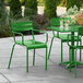 A Lancaster Table & Seating green powder coated aluminum arm chair on a patio with a green table and drinks.