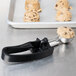 A Vollrath #30 black squeeze handle disher scooping cookie dough onto a tray.