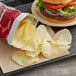A bag of Good's Red Homestyle Potato Chips on a counter next to a burger.