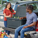 A man and woman sitting in the back of a truck with a CaterGator outdoor cooler.