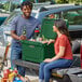 A man and woman sitting on the back of a truck with a CaterGator outdoor cooler.