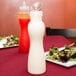 A table set with a salad and two polycarbonate bottles of white liquid with white lids.