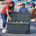 A woman putting a can into a CaterGator outdoor cooler next to a man.