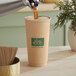 A brown New Roots compostable paper hot cup with coffee being poured into it.