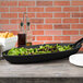 A black oval melamine tray with food on it.