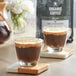 Two glass cups of Crown Beverages Organic Colombian Whole Bean Coffee on a wooden surface.