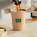 A hand pouring coffee into a New Roots Double Wall Kraft paper hot cup.
