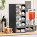 A black KleanTake countertop cup dispenser and lid organizer with 10 slots.