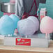 A Carnival King cotton candy holder on a counter with cotton candy cones.