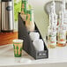 A black ServSense countertop cup and lid organizer holding cups on a counter.