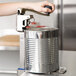 A person using an Edlund heavy duty manual can opener on a counter.