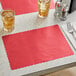 A table with a red Choice paper placemat and glasses of brown and clear liquid with ice cubes.