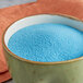 A bowl of blue Great Western Blue Raspberry Popcorn Glaze powder on a table.