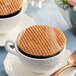 A cup of coffee with a Daelmans caramel stroopwafel on top.