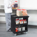 A man using a Cambro black plastic utility cart in a kitchen.