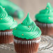 Three cupcakes with green frosting on a silver plate.