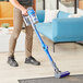 A man using a Lavex Pro cordless stick vacuum to clean a floor.