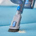 A Lavex Pro blue stick vacuum cleaning a blue surface.
