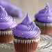 A group of cupcakes with purple frosting on a metal rack.