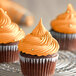 A group of cupcakes with LorAnn Oils orange frosting on a metal rack.