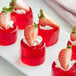 A plate of red jello with strawberries on top.