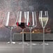 A close-up of three Spiegelau Bordeaux wine glasses filled with different types of wine.