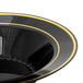 A close-up of a Fineline black plastic soup bowl with gold bands.