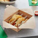 A 3-compartment polypropylene taco holder with tacos in it.