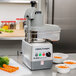 A Robot Coupe food processor with a bowl of shredded carrots.