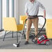 A man using an Atrix red bagless canister vacuum on a yellow chair.