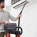 A man using an Atrix ESD-Safe vacuum to clean a black cable near an air conditioner.