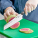 A person using a Kai PRO Master Utility Knife to cut watermelon.