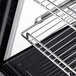 A close up of a metal rack with a black surface inside an Avantco countertop refrigerator.