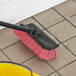 A Lavex bi-level floor scrub brush with a squeegee cleaning a tile floor.