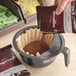 A person pouring Ellis Mezzaroma French Caramel Creme coffee into a coffee filter.