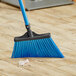 A blue Lavex angled broom head on a wooden floor.