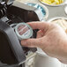 A hand pressing an Ellis Mezzaroma Pumpkin Spice coffee single serve cup onto a coffee machine.