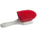 A close-up of a Lavex red and white pot scrub brush with a red handle.