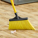 A yellow Lavex broom head on a wooden floor.