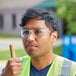 A man wearing Honeywell Uvex safety glasses and a reflective vest holding a hammer.