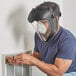 A man wearing a face mask and a Honeywell Uvex Bionic face shield while working on a wall.