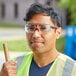 A man wearing red Honeywell safety glasses and a yellow reflective vest holding a hammer.